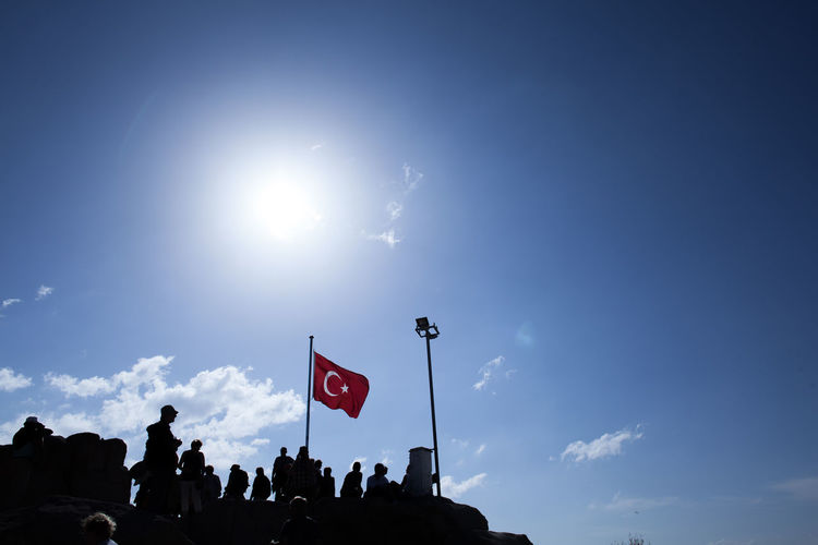 Low angle view of people standing by turkish flag against sky