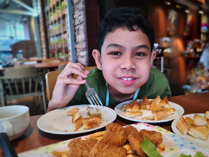 Portrait of kid enjoy eating garlic bread at restaurant