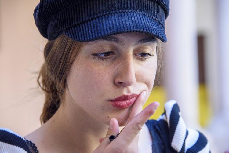 Close-up portrait of young woman holding hat