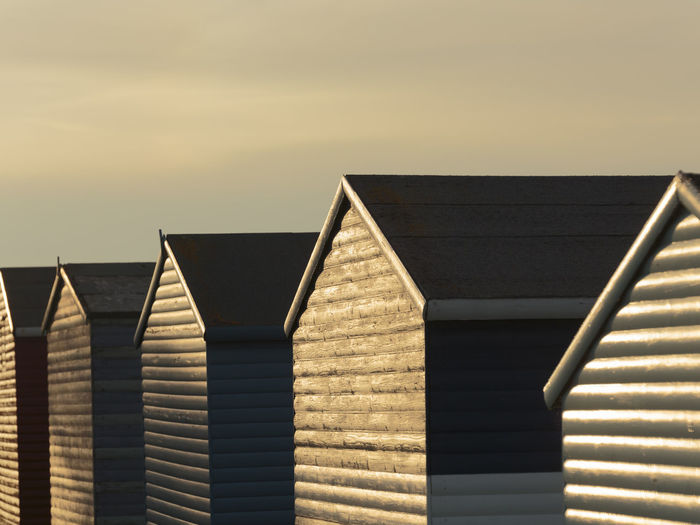Low angle view of beach huts against sky during sunset
