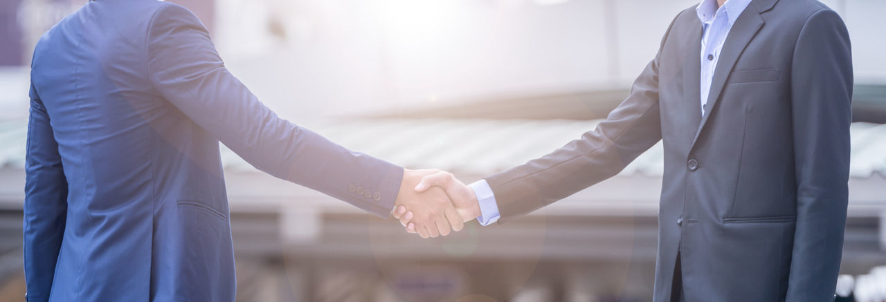 Midsection of businessmen shaking hands in city