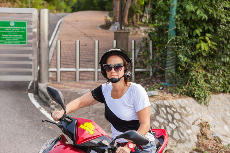 Portrait of woman wearing sunglasses while sitting on motor scooter