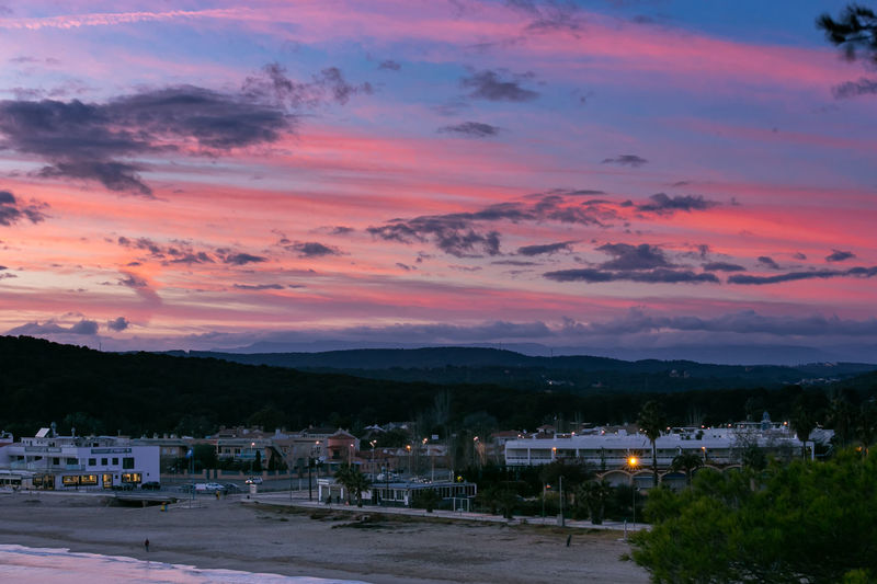 Illuminated cityscape against sky during sunset