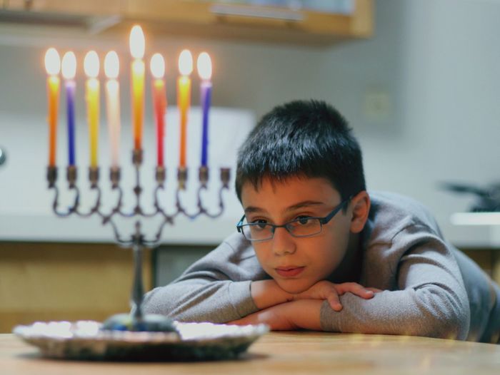 Boy looking at lit candles on hanukkah menorah