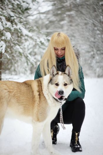 Full length of young woman with dog in snow