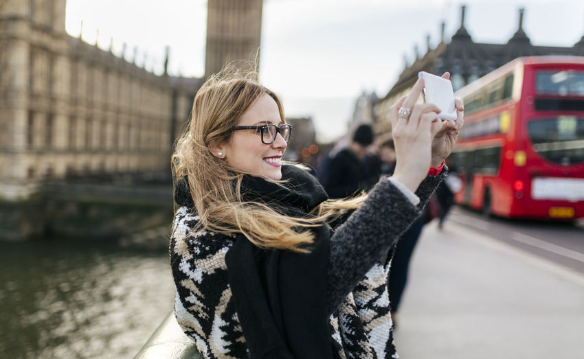 Uk, london, young woman taking a selfie on westminster bridge