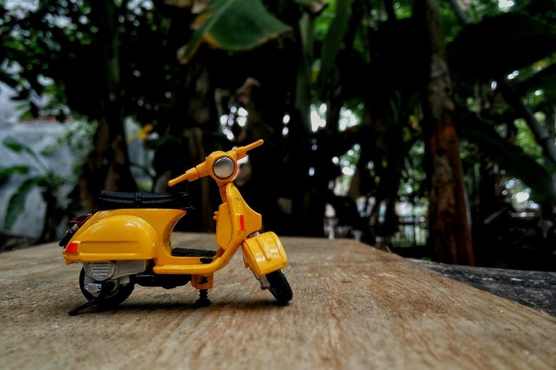 Close-up of yellow miniature motor scooter on table