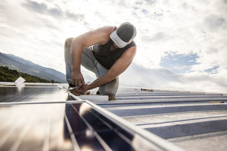 Construction worker installs solar panels on rooftop.