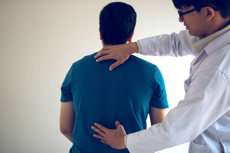 Midsection of chiropractor examining back of patient