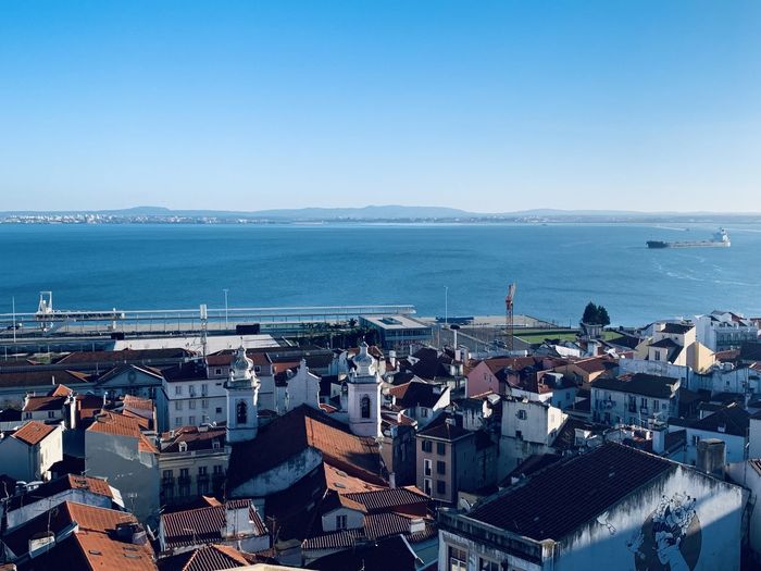 High angle view of townscape by sea against clear sky