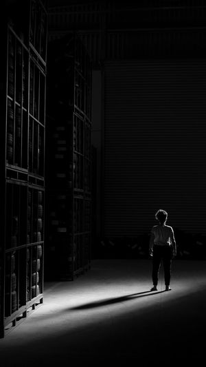 Rear view of woman standing by shelves at night