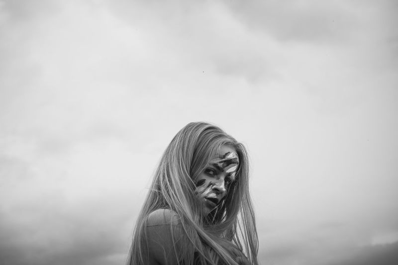 Portrait of woman face covered with powder paint against sky