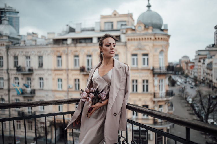 Portrait of woman standing against buildings in city
