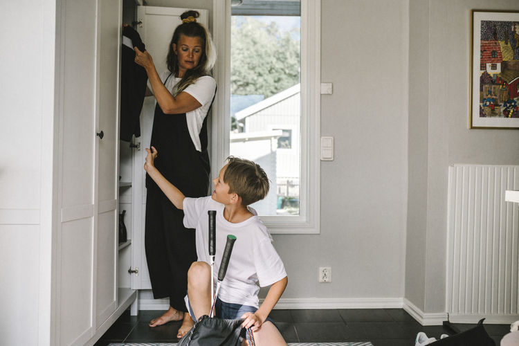 Son talking with mother standing by closet at home