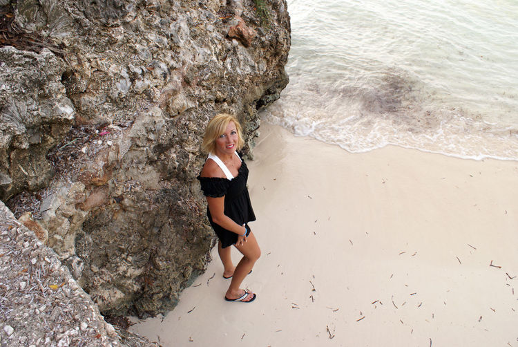 High angle view of woman standing by rock at beach