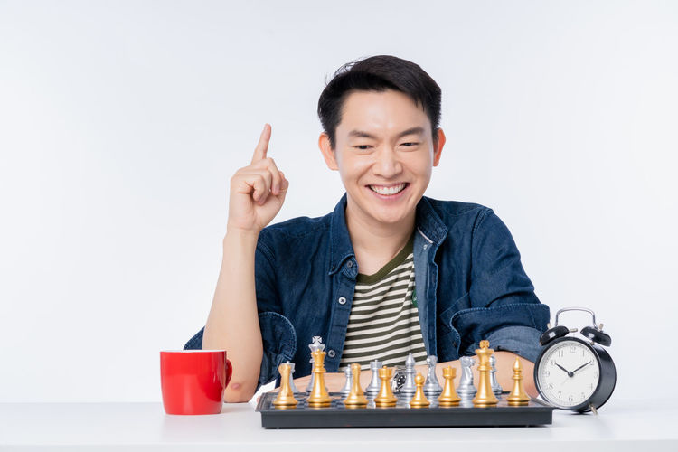 Portrait of smiling young man on table against white background