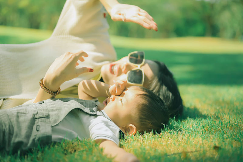 Mother and son lying on grass at park
