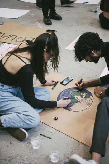 Male and female activists preparing signboard for environmental issue in building