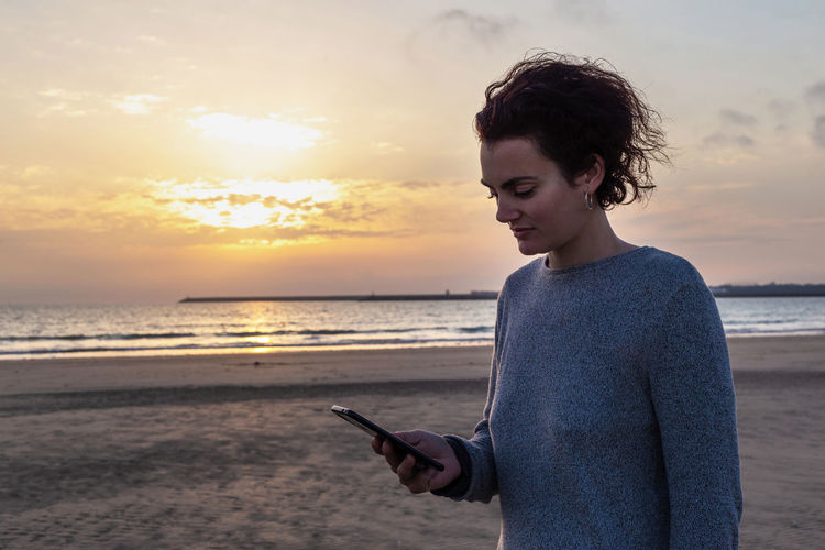 Portrait of a woman using her smartphone on the beach