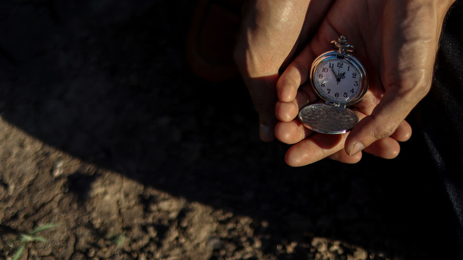 Cropped image of person hand holding watch outdoors