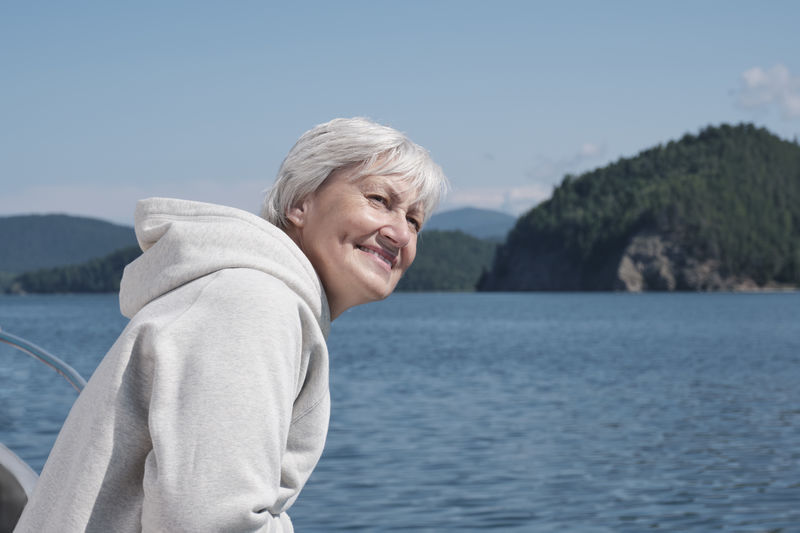 Happy senior caucasian woman with gray hair traveling on boat on lake baikal, russia.