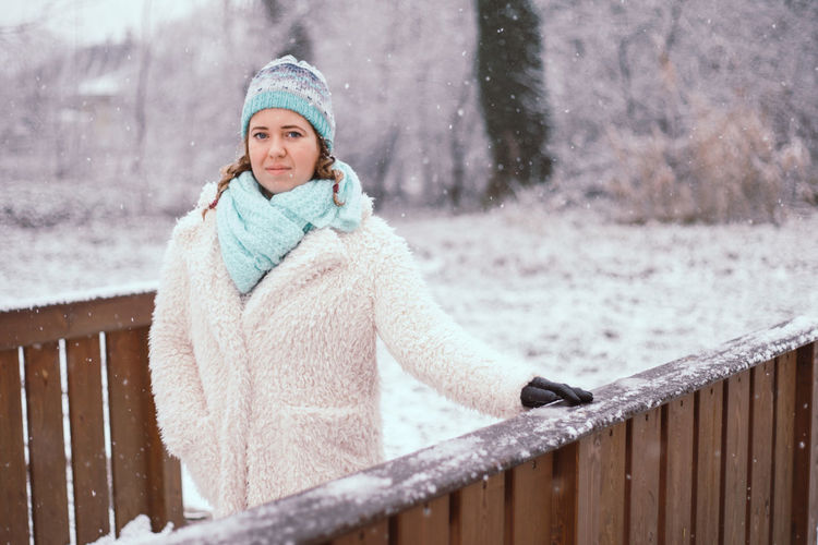 Portrait of young woman standing at park during winter