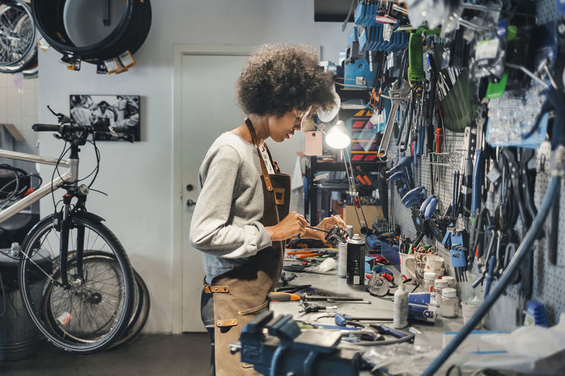 Side view of female mechanic working in bicycle workshop