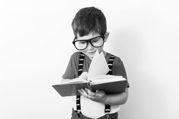 Portrait of boy holding book against white background