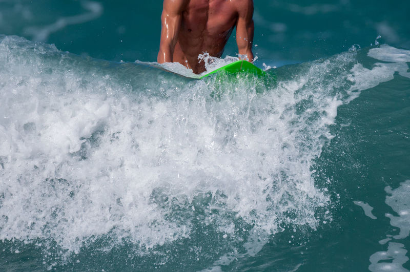 Midsection of man surfing on sea