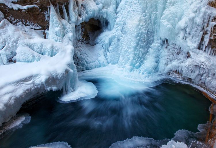 Frozen river flowing through rocks