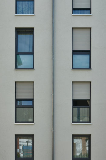 Strict looking perfectly rectangular facade of a residential building with windows and shutters