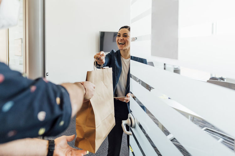 Smiling businesswoman taking food delivery in office