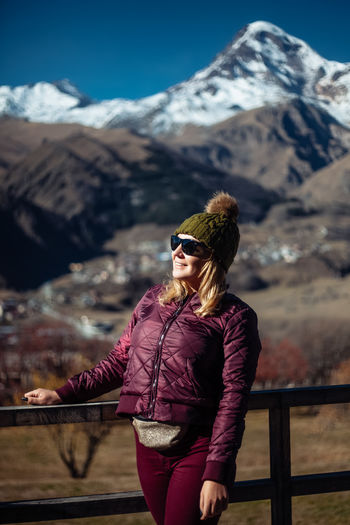 Portrait of young woman standing against mountain range