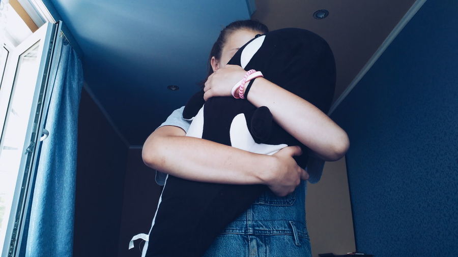 Low angle view of girl embracing stuffed toy