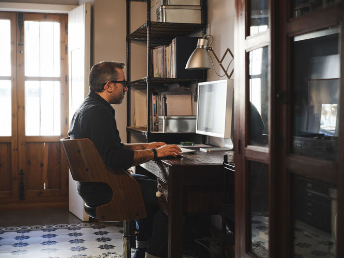 Man working at home desk with computer via internet