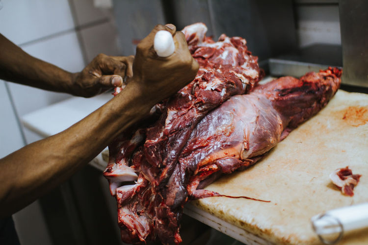 Cropped hands of butcher cutting meat