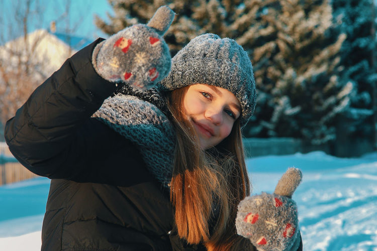 Portrait of woman in warm clothing gesturing thumbs up during winter