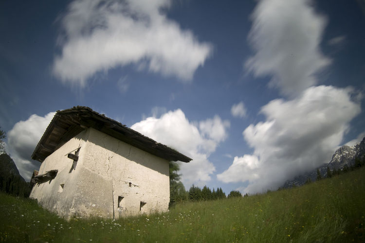 Low angle view of cottage on field against sky