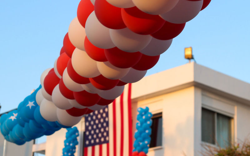 Low angle view of balloons by building with american flag