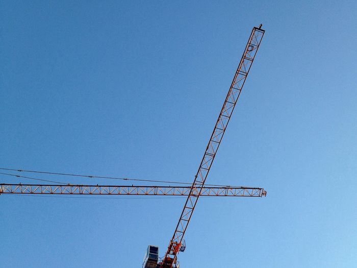 Low angle view of crane against clear blue sky