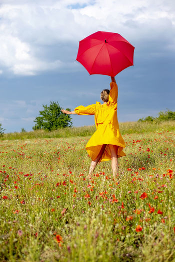 Rear view of woman with umbrella against sky