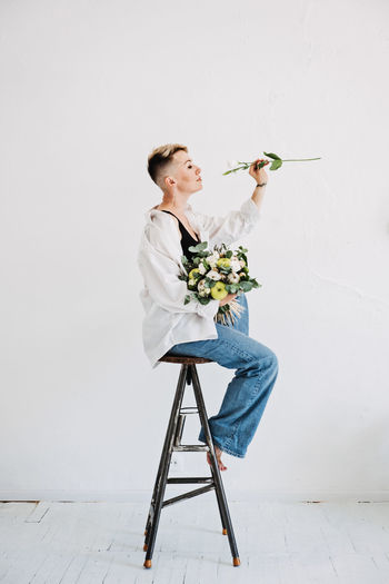 Portrait of bride holding bouquet against white background