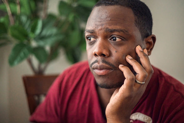 Young depressed or anxious african american man in room at home sitting