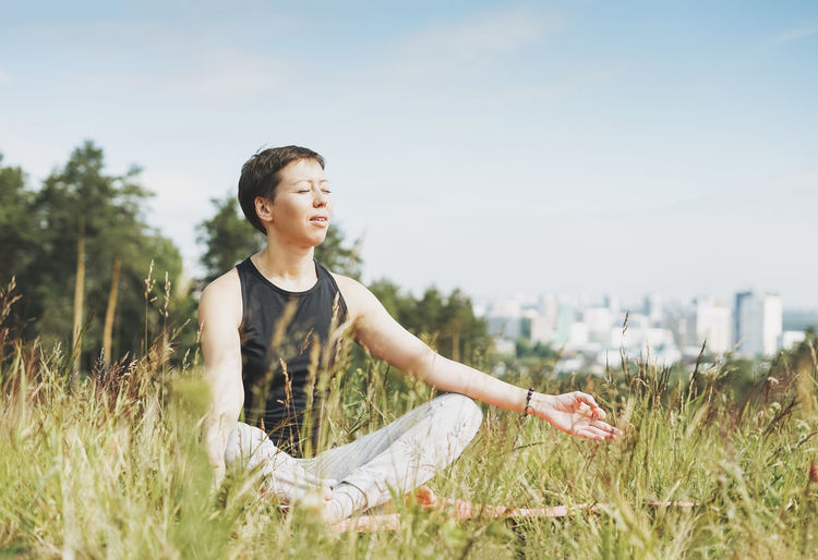Young smiling woman practice yoga outdoors in the city. new normal social distance
