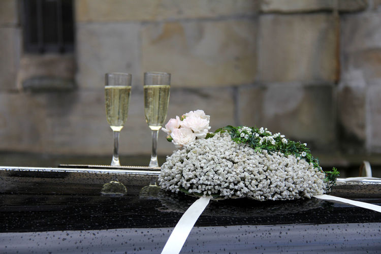 Close-up of champagne and flowers on wedding car