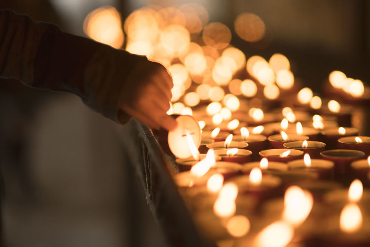 Close-up of hand holding lit candles