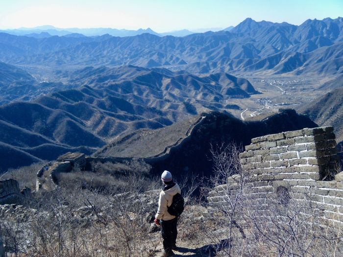 Rear view of man standing by great wall of china on mountain