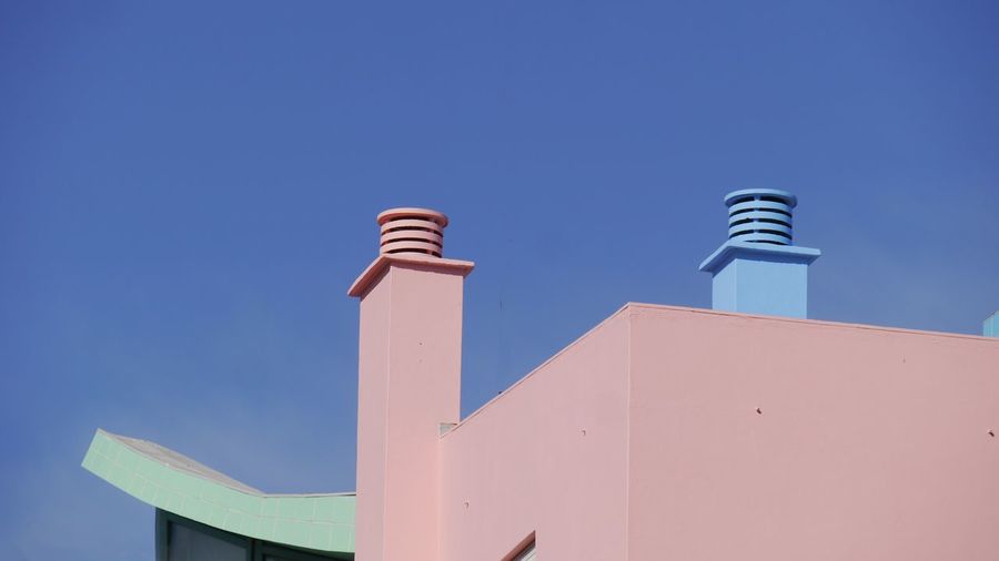 Low angle view of pastell colored part of building against clear blue sky