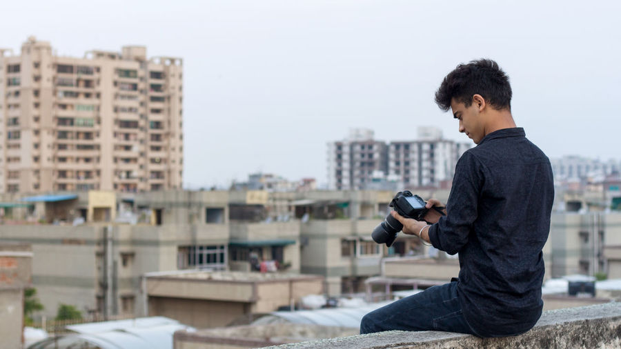 Young photographer exploring terrace while clicking photographs in his dslr camera. world pandemic.