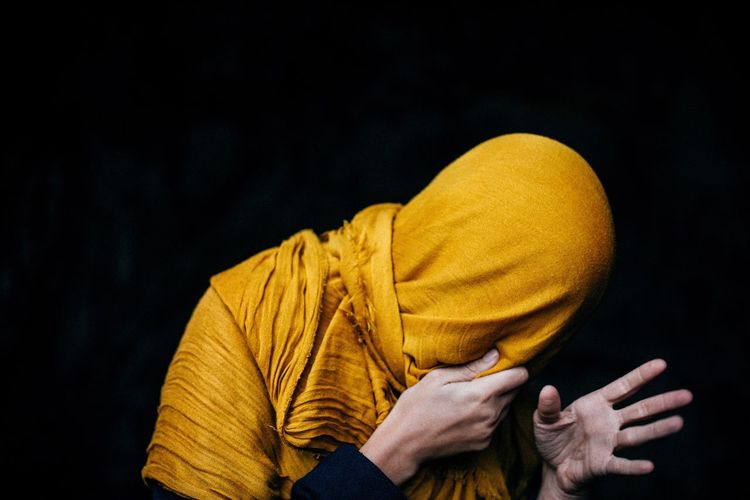 Man wrapped in yellow scarf against black background